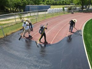 A crew works to resurface a running track