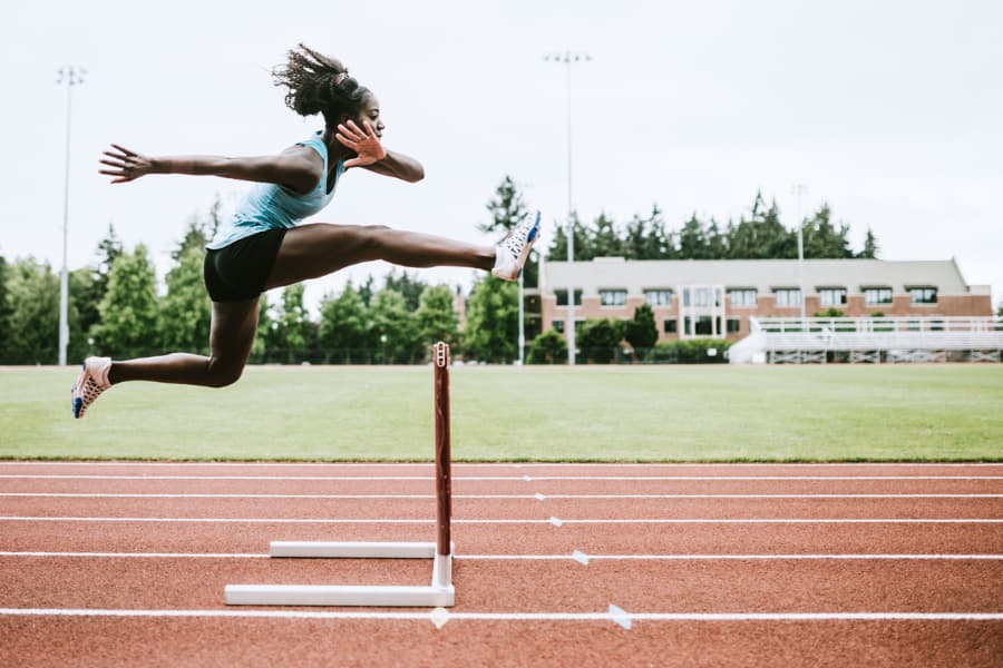 Runner jumping over a hurdle on a track