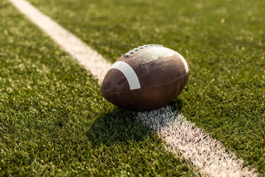 Football resting on artificial turf playing field