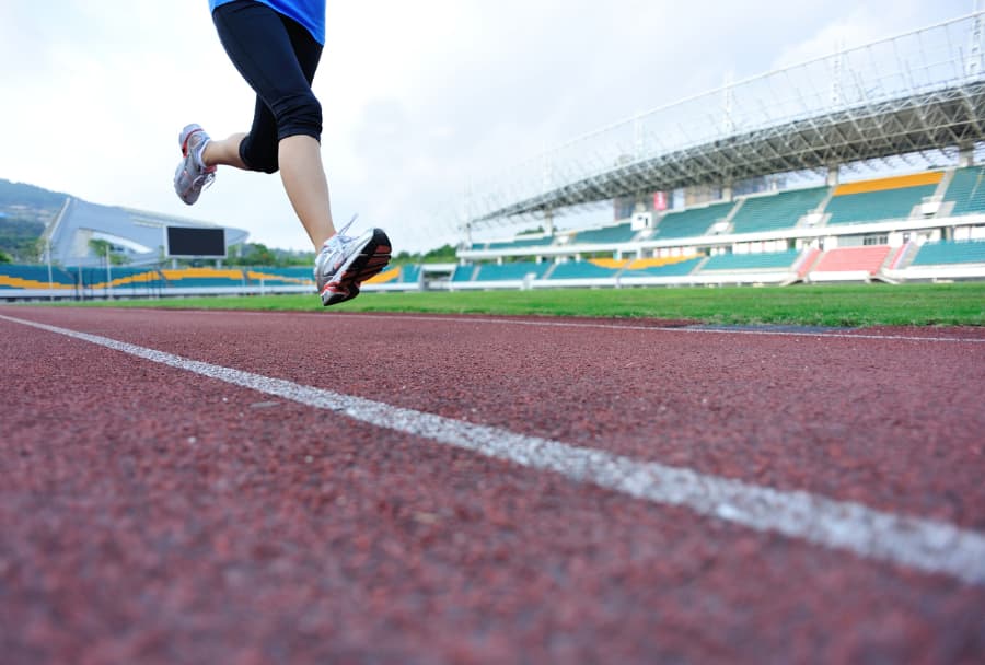 Athlete sprinting on running track inside of stadium