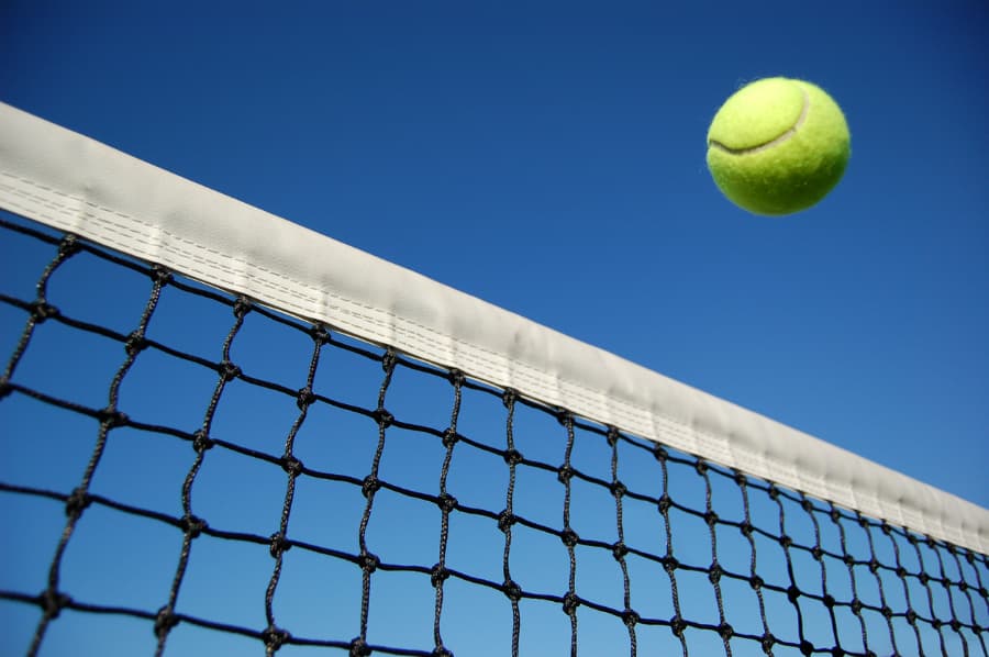 Close-up view of tennis ball flying over net after being hit